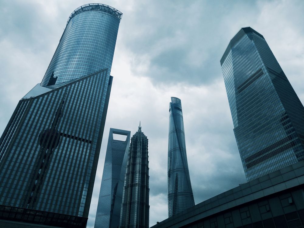Shanghai skyscrapers viewed from street level beneath a cloudy sky